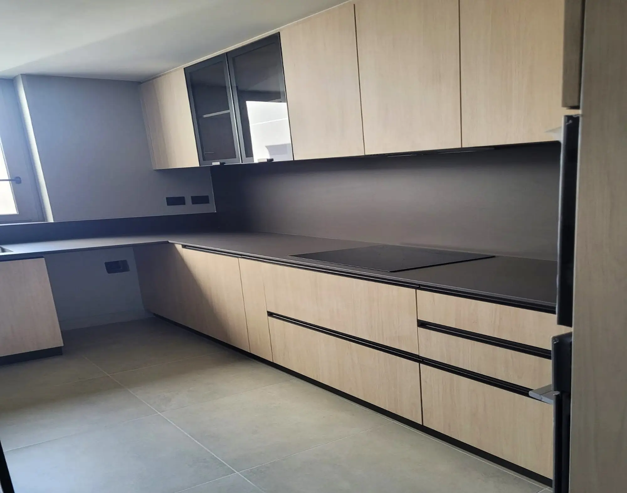 Cocina moderna con muebles en melamina madera clara, cubierta de cuarzo oscuro y electrodomésticos empotrados, diseño exclusivo de Style Muebles en Chile